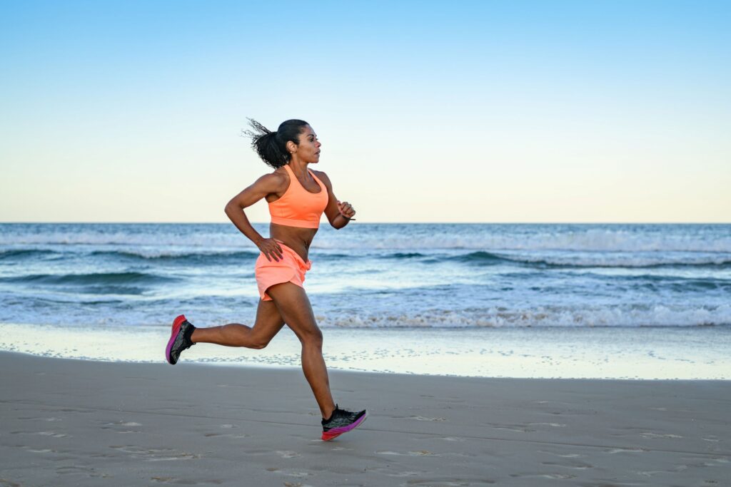 Red Light Therapy for Athletes 1 Woman jogging on beach at sunset.