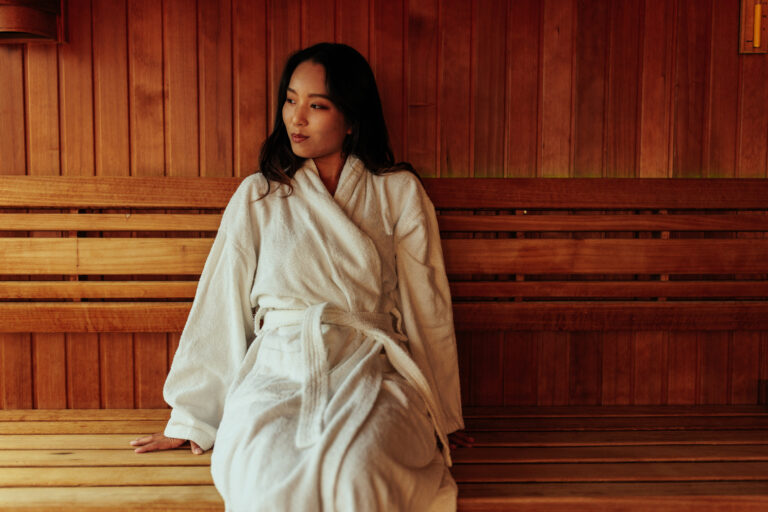Woman in hot sauna with robe on relaxing