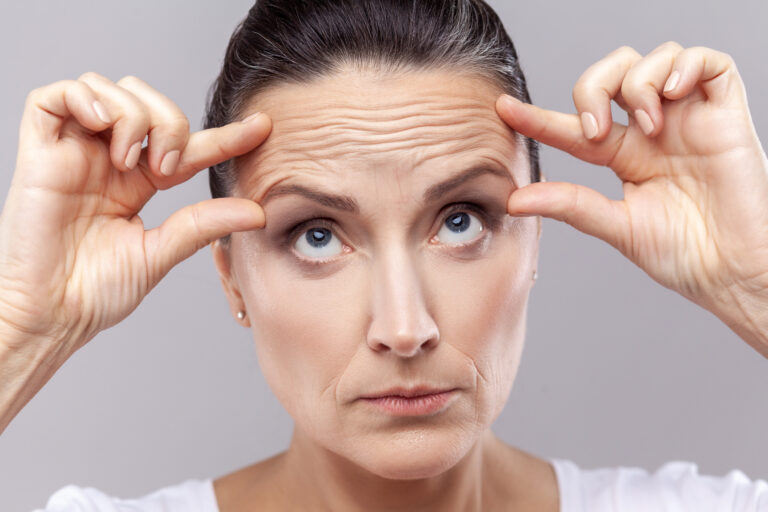 Woman examining her forehead on how to reduce wrinkles