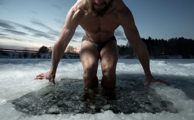 Man entering icy water outdoors for cold plunge therapy
